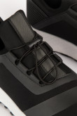 Tenis deportivos negros con materiales y suelas en contraste