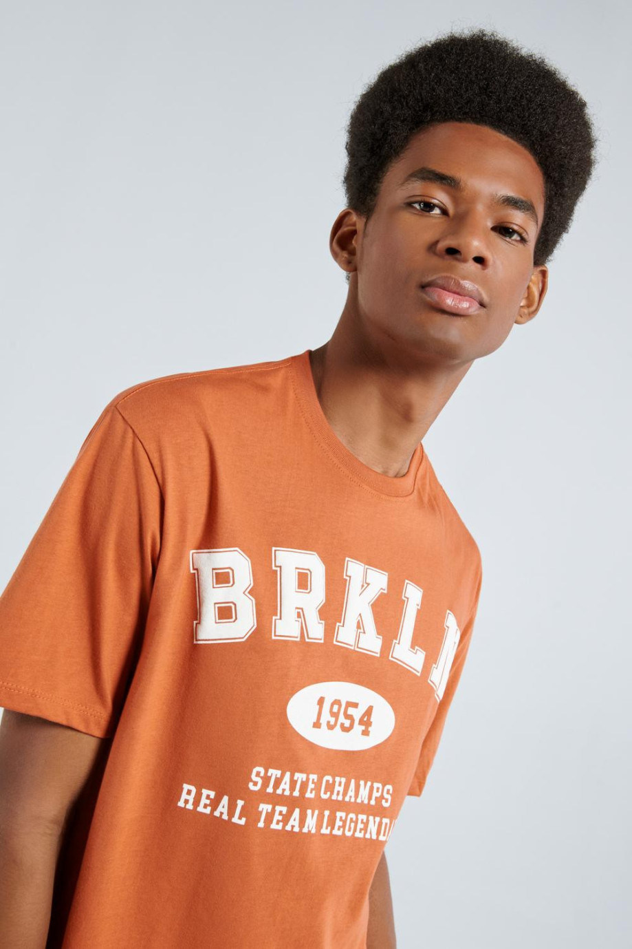 Camiseta naranja con cuello redondo y texto blanco college