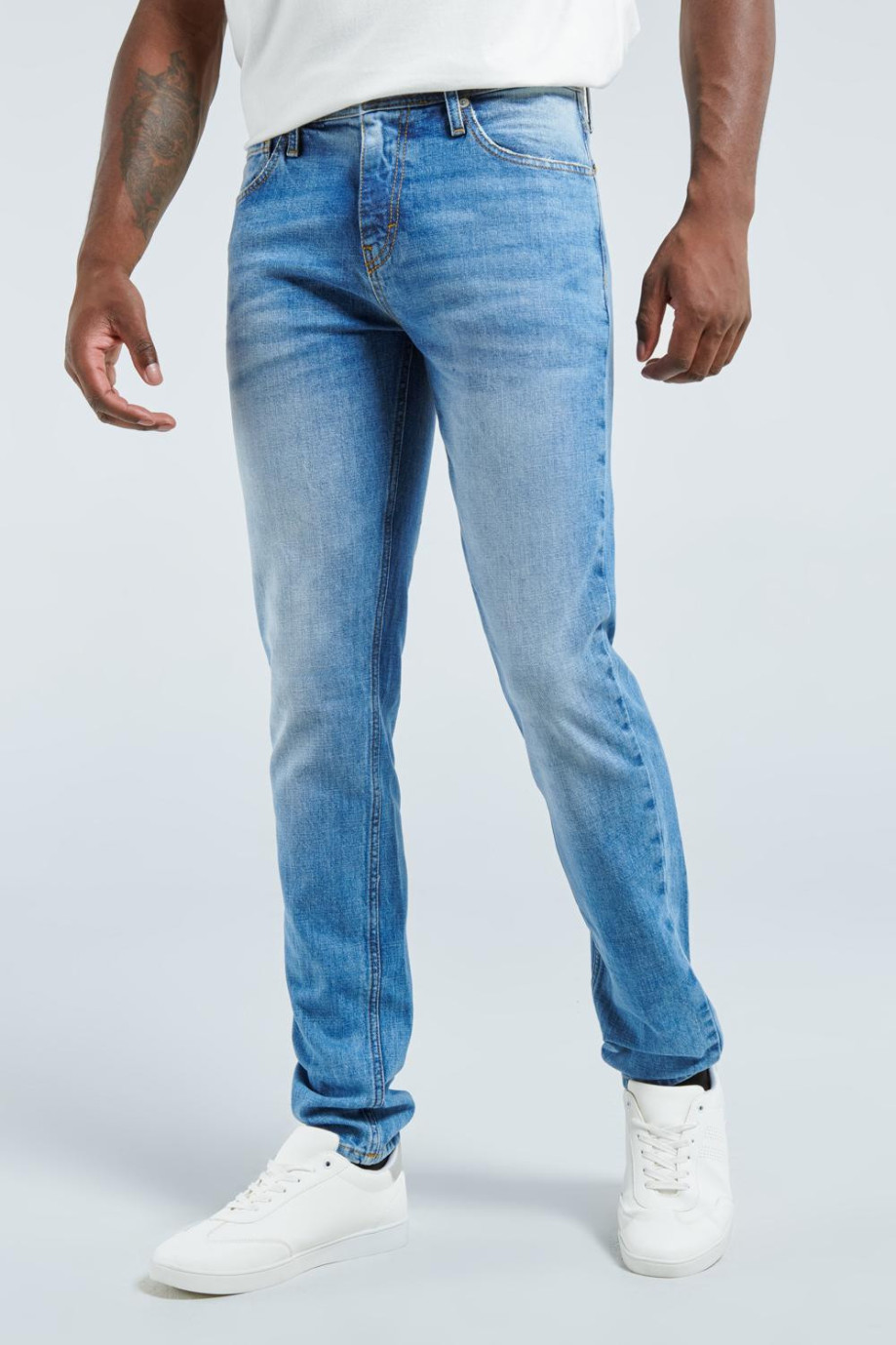 Jean azul medio slim con desgastes sutiles de color y 5 bolsillos