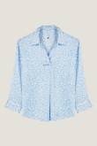 Blusa azul clara con cuello camisero, manga 3/4 y diseños de flores blancas