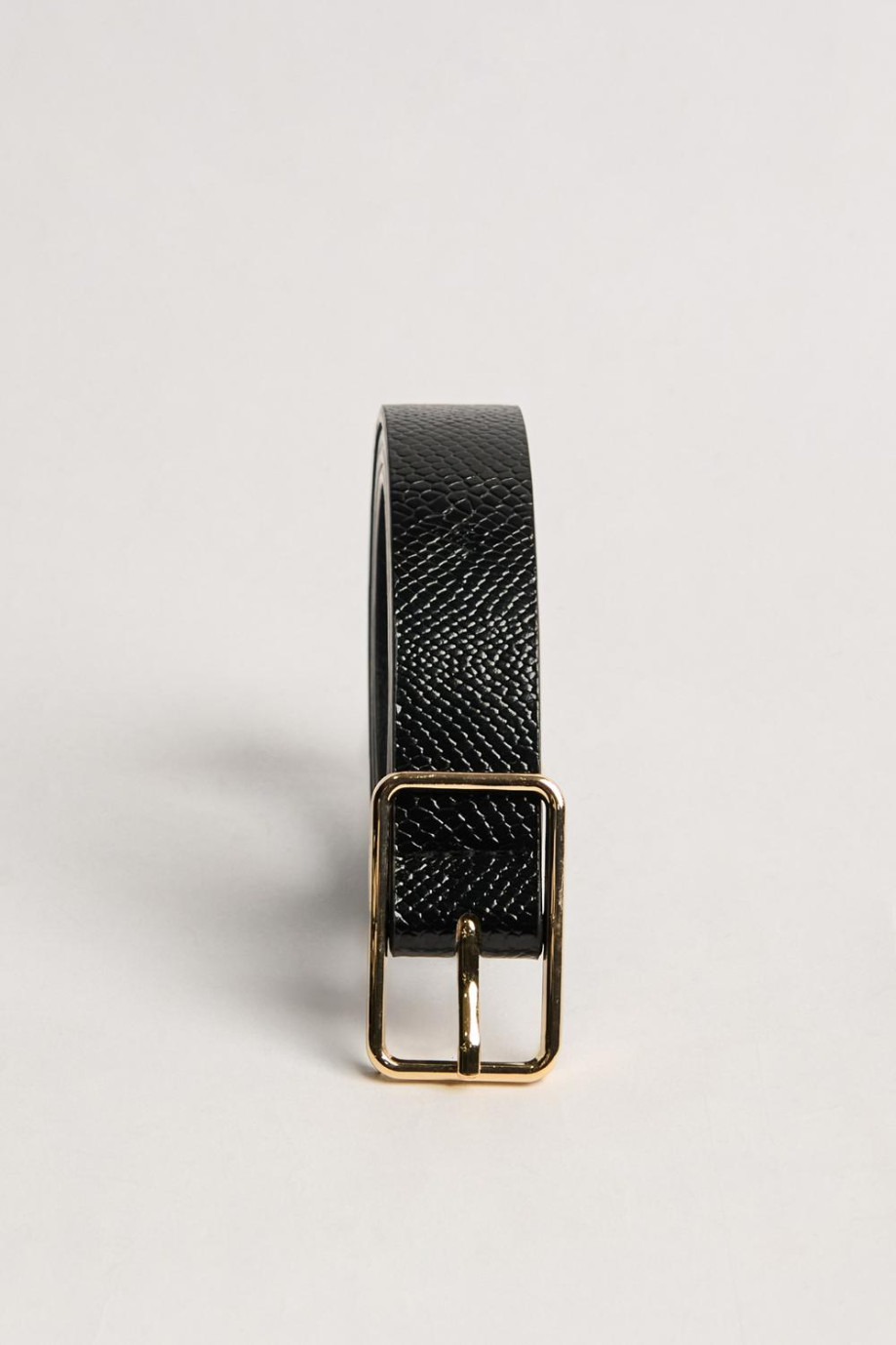 Cinturón femenino en color café oscuro, elaborado en sintético con textura tipo reptil, hebilla metálica ovalada y punta con for