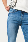 Jean skinny azul claro con desgastes localizados y tiro bajo